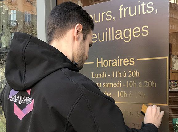 Pose d'un sticker horaire sur une porte de fleuriste