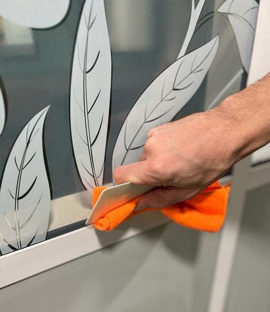 Le poseur sèche les coins de la vitrophanie avec un microfibre